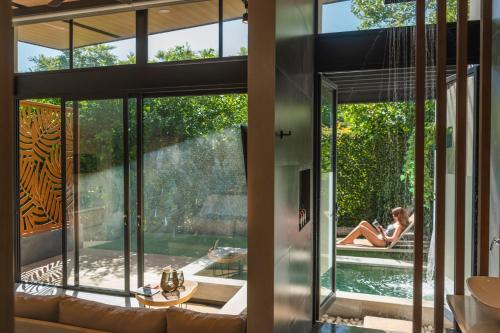 a house with a pool and a woman sitting on a couch at Epic Tamarindo Boutique Hotel in Tamarindo