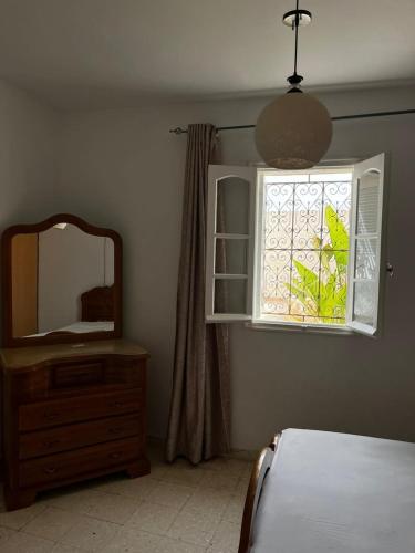 ein Schlafzimmer mit einem Spiegel, einer Kommode und einem Fenster in der Unterkunft Houmet souk RDC 05 in Houmt Souk