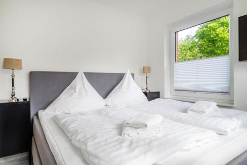 a large white bed with white pillows and a window at Die Zimmerei 2, zentrale Lage, Obergeschoss mit Terrasse in Greetsiel
