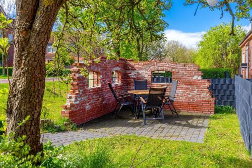 a brick wall with a table and chairs in a yard at Die Zimmerei 2, zentrale Lage, Obergeschoss mit Terrasse in Greetsiel