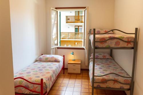 Un dormitorio con dos literas y una ventana. en Villa Verde, en Eraclea Mare