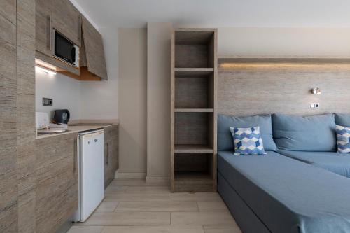 a small bedroom with a blue bed and a kitchen at Leonardo Royal Hotel Mallorca Palmanova Bay in Palmanova