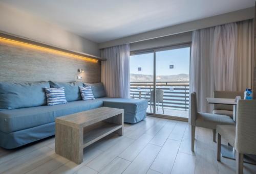 a living room with a blue couch and a table at Leonardo Royal Hotel Mallorca Palmanova Bay in Palmanova