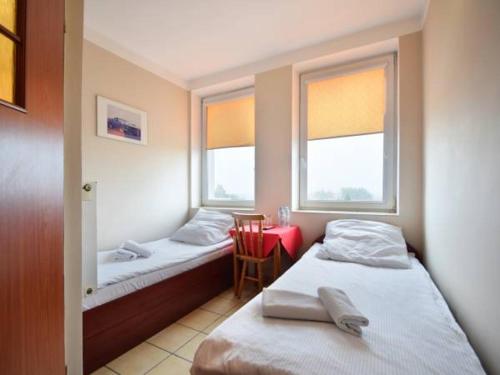 a room with two beds and a chair and two windows at Hotelik Bej in Tuszyn