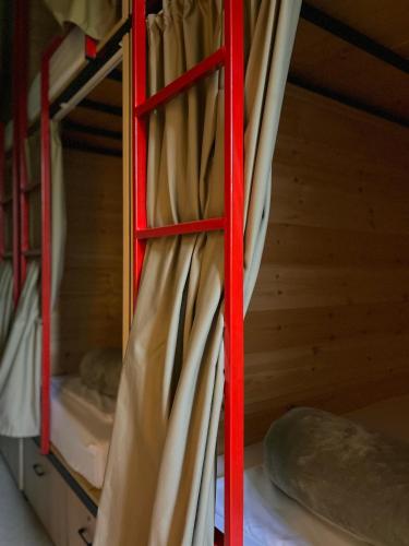 eine rote Leiter in einem Etagenbett mit Vorhängen in der Unterkunft Queen-V Hostel in Vlorë