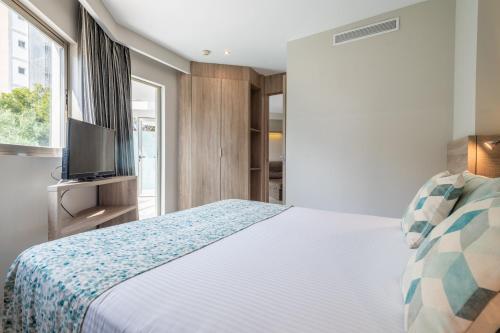 a bedroom with a bed and a tv and a window at Leonardo Royal Hotel Mallorca in Palmanova