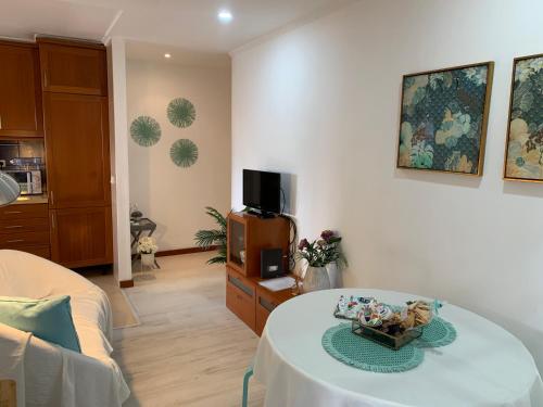 a living room with a table and a tv at Your sweet home near Aveiro! in Marco da Oliveirinha