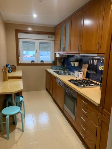 a kitchen with wooden cabinets and a stove top oven at Your sweet home near Aveiro! in Marco da Oliveirinha