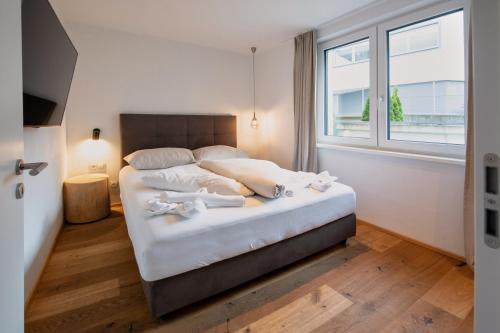 a bedroom with a bed with white sheets and a window at HEAVEN 7 SUITE - Garden Apartment with Private Whirlpool in Zillertal, presented by AlpenLuxus in Fügen