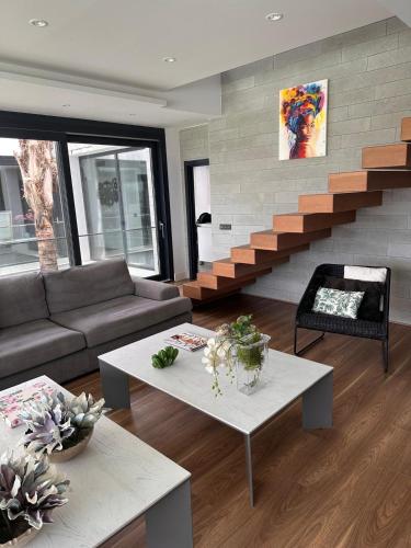 a living room with a couch and tables and stairs at Villa Essencia in Zahara de los Atunes