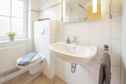 a white bathroom with a sink and a toilet at Ferienhäuser Greetsiel in Ostfriesland in Greetsiel