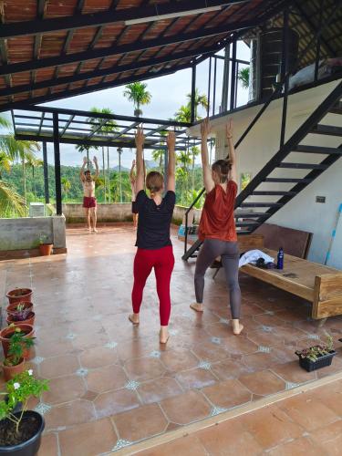 two women are performing a yoga pose in a patio at Ananda Holiday Home in Ambalavayal