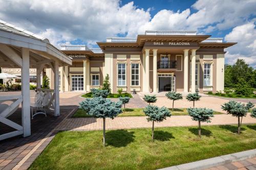 a large building with trees in front of it at Hotelik Bej in Tuszyn