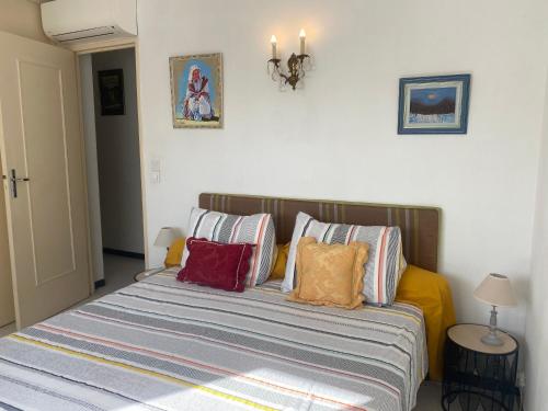 - un lit avec des oreillers colorés dans une chambre dans l'établissement Au cœur de Cavalaire sur mer, à Cavalaire-sur-Mer