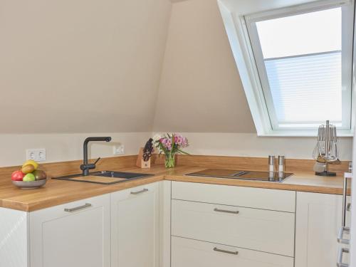 a kitchen with white cabinets and a sink and a window at Appartement Möwe in Westerland (Sylt)