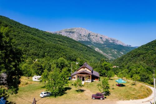 a house on a hill with mountains in the background at Etno domaćinstvo Dvožak in Pluzine