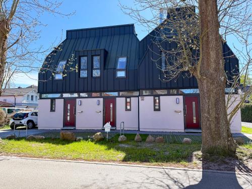 una casa con puertas rojas y techo negro en Kraanstiet 2, en Zingst
