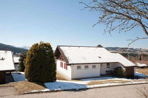 a white house with a snow covered roof at Ferienhaus Gamssteige im Feriendorf Reichenbach G19 in Nesselwang