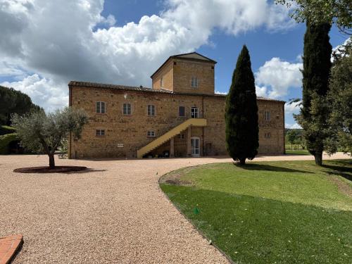 a large brick building with a tree in front of it at Bioagriturismo il cerreto in Pomarance