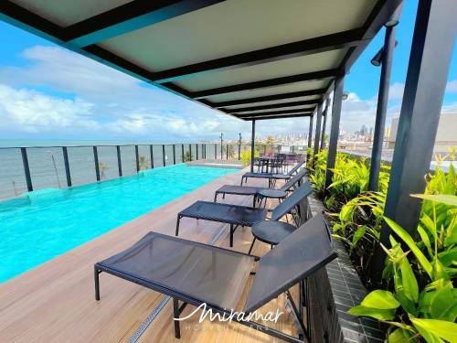 a row of chairs sitting on a deck next to a swimming pool at Beach Haus in Tambaú