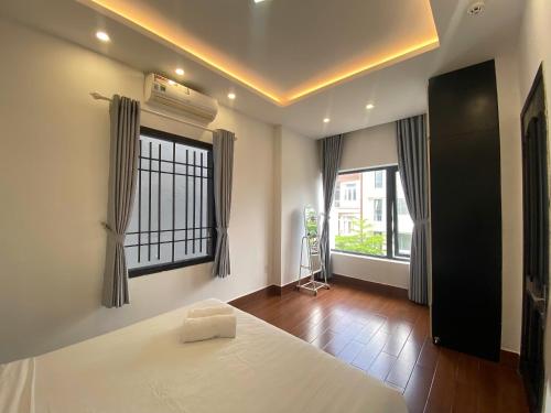 a bedroom with a white bed and two windows at Han Riverside in Da Nang