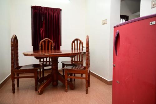a dining room with a table and chairs and a red refrigerator at City Villa in Kodaikānāl