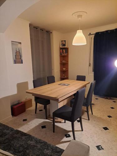 a dining room with a wooden table and chairs at Chambre dans maison paisible in La Ville-du-Bois