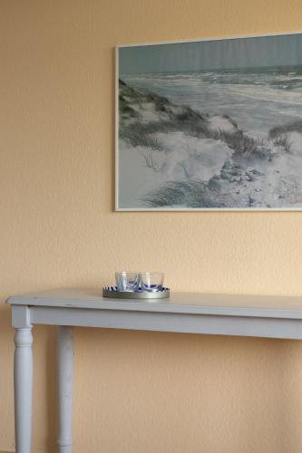 a table with two glasses on it next to a painting at App Meerzeit in List