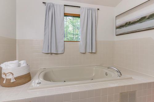 La salle de bains est pourvue d'une baignoire blanche et d'une fenêtre. dans l'établissement Pool Access Peaceful Cabin in The Woods Resort!, à Hedgesville