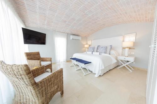 a white bedroom with a bed and a chair at Casa La Merced by Mustique in Cartagena de Indias