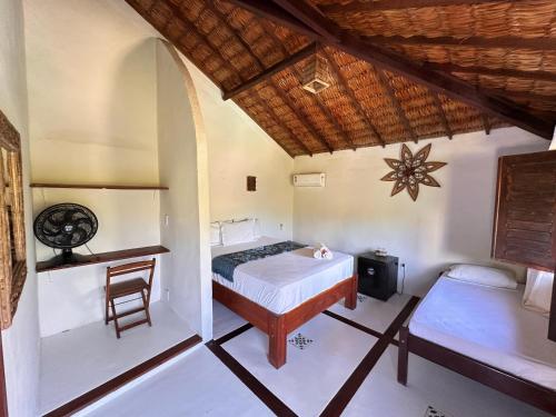 a bedroom with a bed and a desk and a chair at Pousada Bate Vento in Itarema