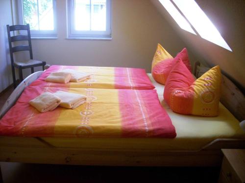 een bed met roze en gele lakens en kussens bij Ferienhaus zur Kranichweide in Bodstedt