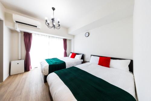 a bedroom with two beds and a window at Riverside Inn Hakata in Fukuoka