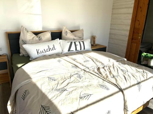 a bed with a white comforter and pillows at Ferienhaus HarzHase in Harzgerode