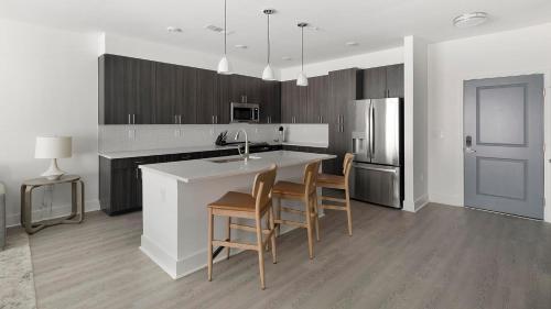 a kitchen with a kitchen island with chairs and a sink at Landing at Station at Crestline - Mountain Brook in Mountain Brook
