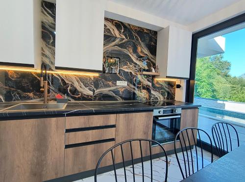 a kitchen with a sink and a table with chairs at Villa vista mare in Zagrađe