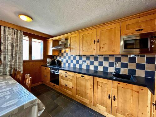 une cuisine avec des armoires en bois et un comptoir noir dans l'établissement Bel appartement rénové 8 pers, pistes et commerces à proximité - FR-1-452-76, aux Menuires