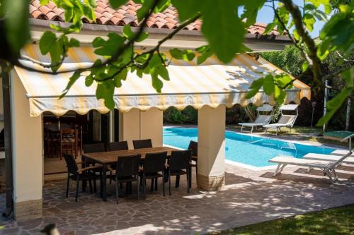 a patio with a table and chairs next to a pool at Faggio 14a in Isola Albarella