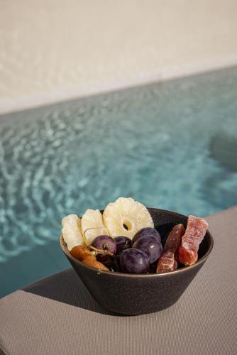 a bowl of fruit on a table next to a pool at PATHOS Private Villas - Adults Only in Samos