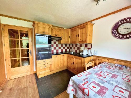 une cuisine avec des armoires en bois et une horloge au mur dans l'établissement Appartement cosy 4 pers. aux Menuires, proche pistes et services - FR-1-452-116, aux Menuires
