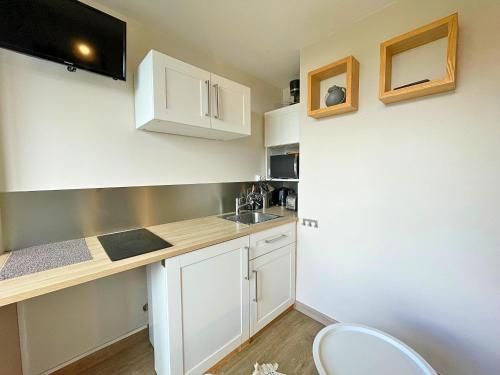une petite cuisine avec des armoires blanches et un évier dans l'établissement Studio cosy rénové, ski aux pieds, cœur de la Croisette pour 2 pers., Les Ménuires - FR-1-452-71, aux Menuires