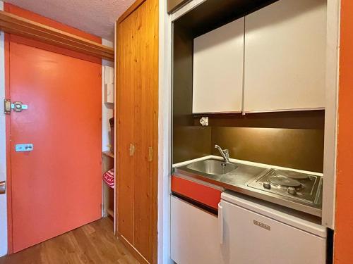 Il comprend une petite cuisine avec un évier et une porte rouge. dans l'établissement Studio confortable au pied des pistes avec animaux permis - FR-1-452-221, aux Menuires