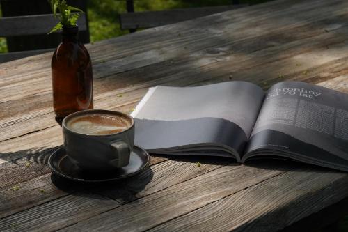 an open book and a cup of coffee on a wooden table at Leśniczówka u Zięby in Kościelisko
