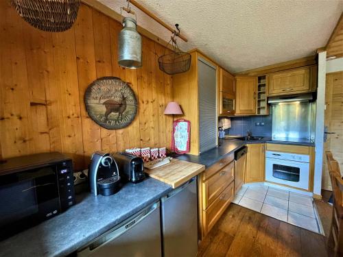 une cuisine avec des armoires en bois et un comptoir dans l'établissement Appartement confort 7 pers, pistes, Sud-Ouest, WIFI, casier à skis, 3 ch, 2 sdb - FR-1-452-384, aux Menuires