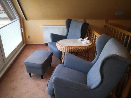 a living room with two blue chairs and a table at Freude Reetgedecktes Ferienhaus in Ueckeritz