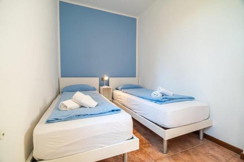 two beds in a small room with blue walls at Mare 2 in Isola Albarella