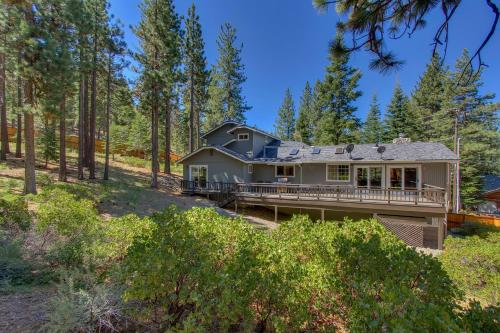 a house with a large deck in the woods at Prima Del Norte - Hot tub Pool Table Arcade Game in South Lake Tahoe