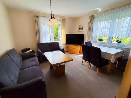 una sala de estar con un sofá y una mesa en Haus am Strand, en Bensersiel
