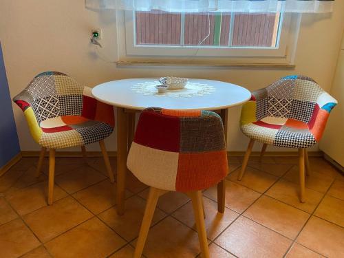 a table with three chairs and a table with a plate on it at Ferienwohnung Bunte Wiese in Parchtitz