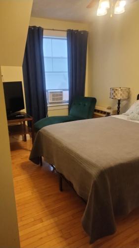 a bedroom with a bed and a chair and a window at Auberge Vue d'la Dune - Dune View Inn in Bouctouche